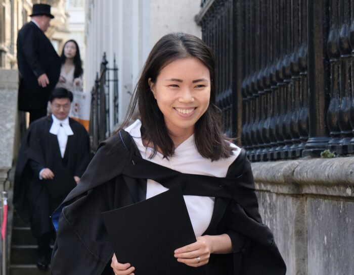 Colour photo of a young woman going up the Senate House side entrance stairs.