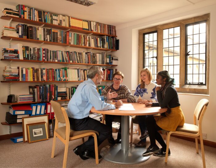Colour image of a tutor and his students during a supervision.